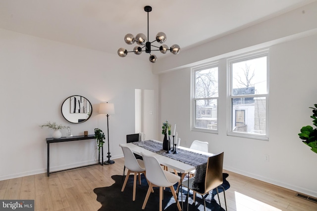 dining space with a chandelier, visible vents, baseboards, and light wood-style floors