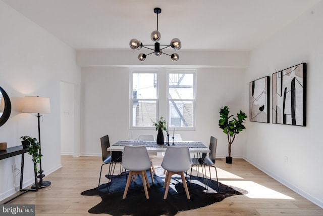 dining space featuring baseboards, an inviting chandelier, and light wood-style flooring