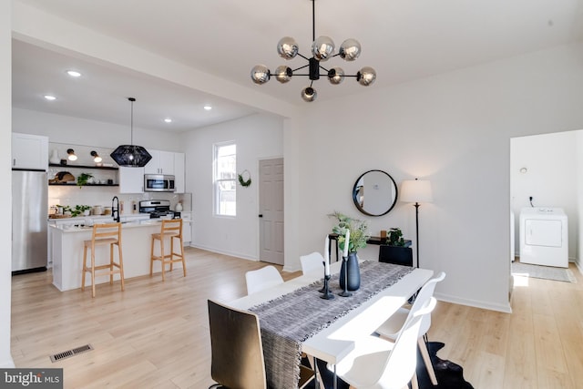 dining area with visible vents, recessed lighting, light wood finished floors, washer / dryer, and a chandelier