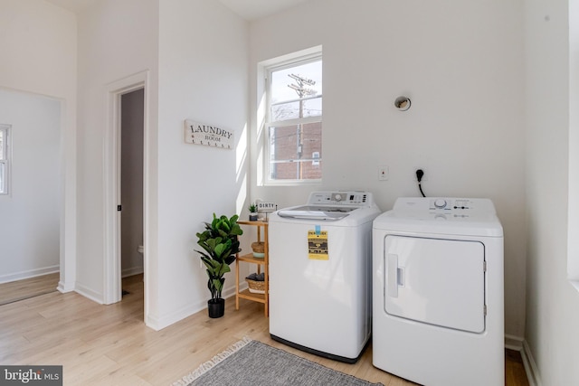 laundry room with laundry area, light wood-style flooring, baseboards, and washing machine and clothes dryer