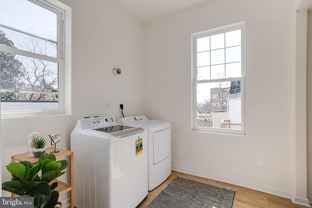 laundry area featuring laundry area, light wood-type flooring, baseboards, and washing machine and clothes dryer