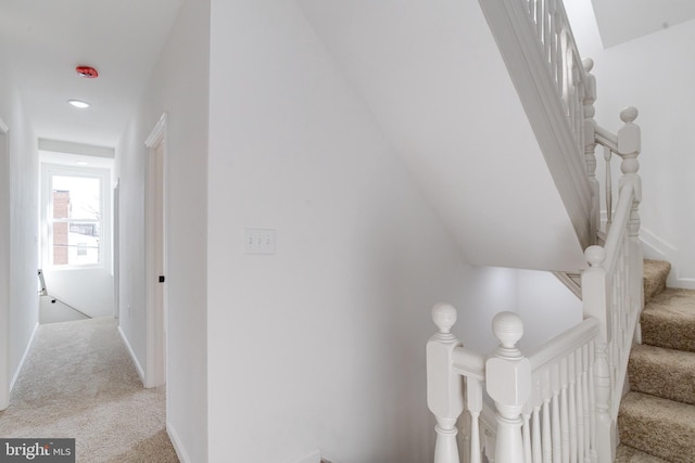 hallway featuring light colored carpet and baseboards