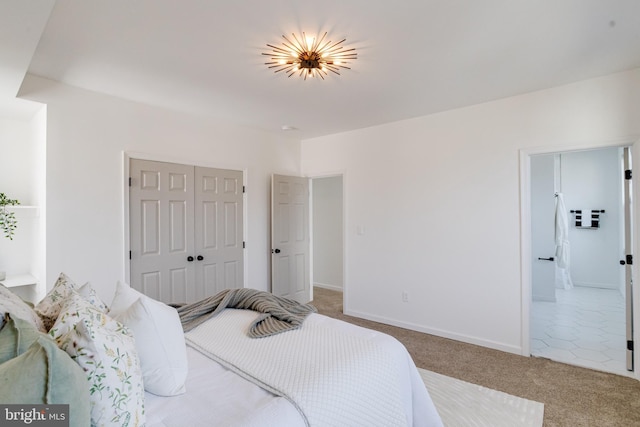 carpeted bedroom featuring a closet, baseboards, and ensuite bathroom