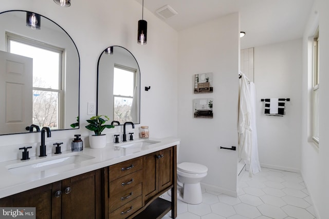 full bath with plenty of natural light, toilet, visible vents, and a sink