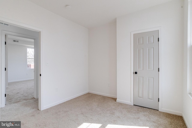 carpeted empty room featuring baseboards and visible vents