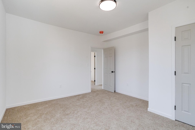 carpeted spare room featuring baseboards