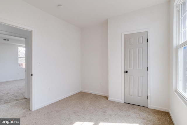 empty room featuring visible vents, carpet, and baseboards