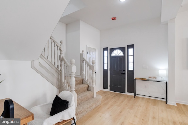 foyer featuring stairs, wood finished floors, and baseboards