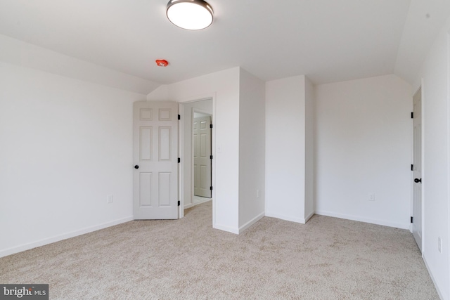 carpeted spare room with vaulted ceiling and baseboards