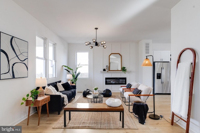 living room featuring baseboards, light wood-style floors, and an inviting chandelier