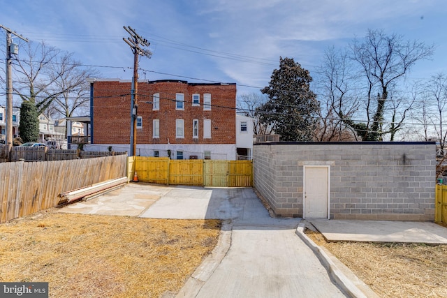 exterior space featuring a gate, concrete block siding, and fence