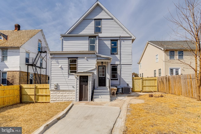 view of front of home with a gate, central AC unit, and a fenced backyard