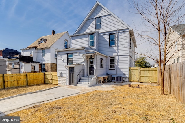 view of front facade with a gate, cooling unit, and fence private yard