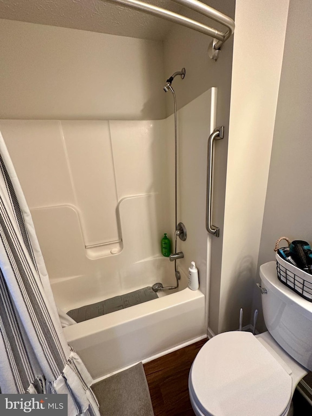 bathroom with wood finished floors, toilet, and shower / bathtub combination with curtain