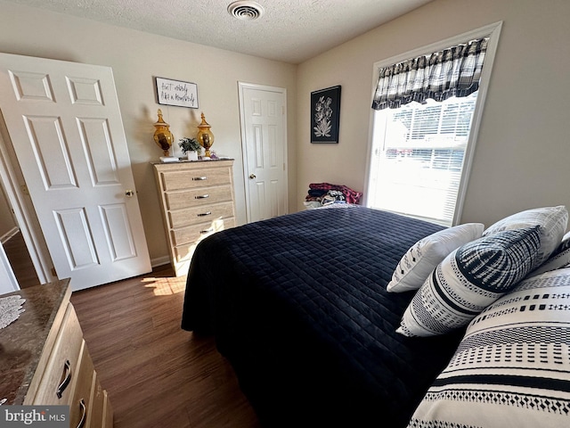 bedroom featuring visible vents, dark wood-style flooring, and a textured ceiling