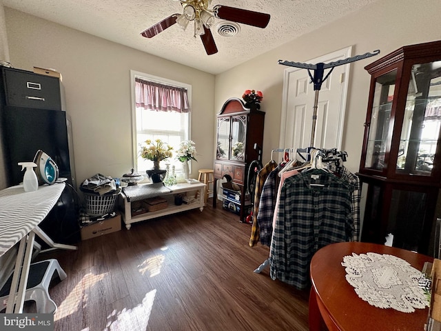 interior space featuring visible vents, a textured ceiling, dark wood-type flooring, and ceiling fan