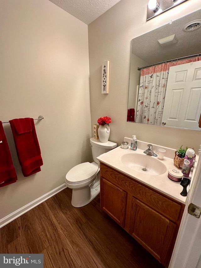 bathroom featuring vanity, wood finished floors, visible vents, a textured ceiling, and toilet