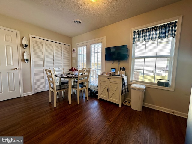 dining area featuring visible vents, a healthy amount of sunlight, and dark wood-style flooring