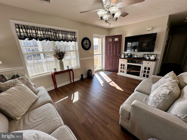 living room featuring baseboards, a textured ceiling, wood finished floors, and a ceiling fan