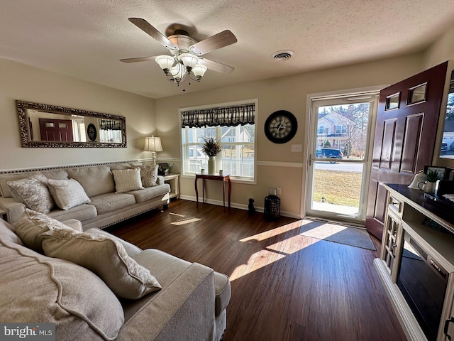 living room featuring visible vents, a textured ceiling, wood finished floors, and a ceiling fan