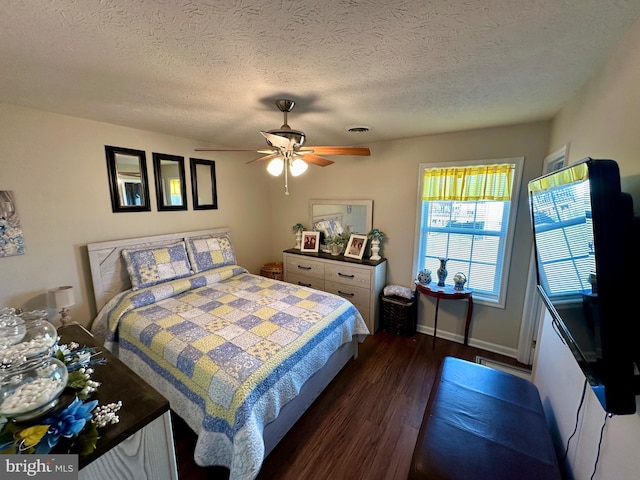 bedroom featuring visible vents, baseboards, dark wood finished floors, a textured ceiling, and a ceiling fan