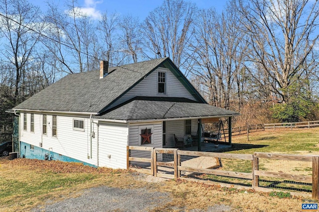 view of front of house with a chimney, a shingled roof, and fence