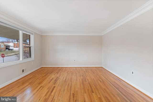 spare room with visible vents, baseboards, crown molding, and light wood finished floors