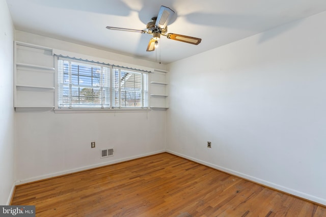 unfurnished room featuring ceiling fan, visible vents, baseboards, and wood finished floors