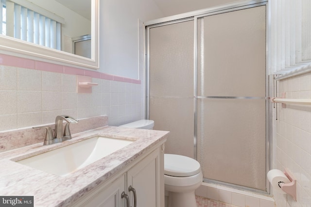 full bathroom with toilet, tile walls, a stall shower, and vanity