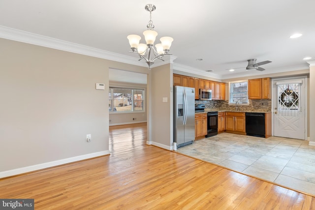 kitchen with light wood-style flooring, a sink, decorative backsplash, black appliances, and crown molding