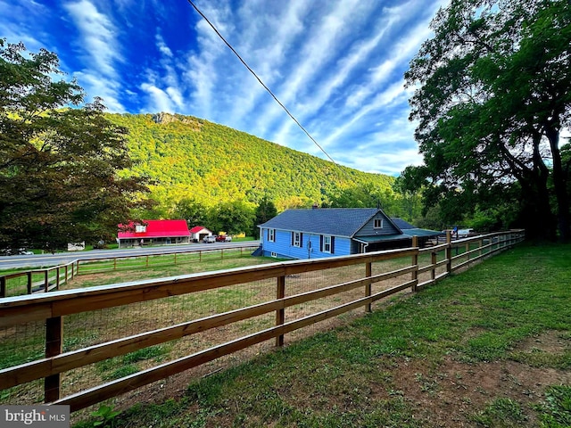 view of yard with a rural view, a mountain view, a view of trees, and fence