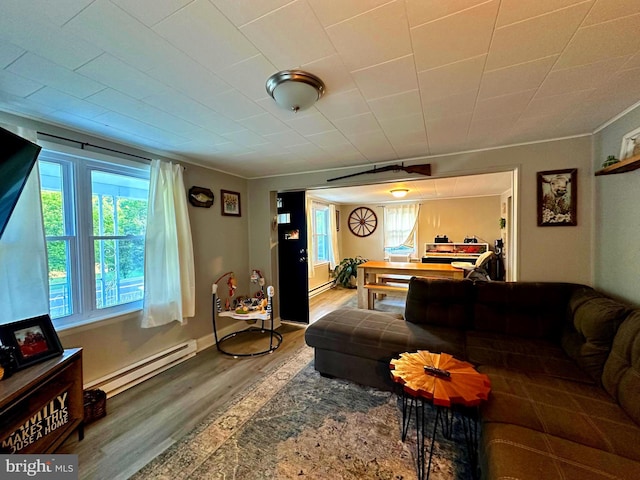 living room with a baseboard heating unit, wood finished floors, and baseboards