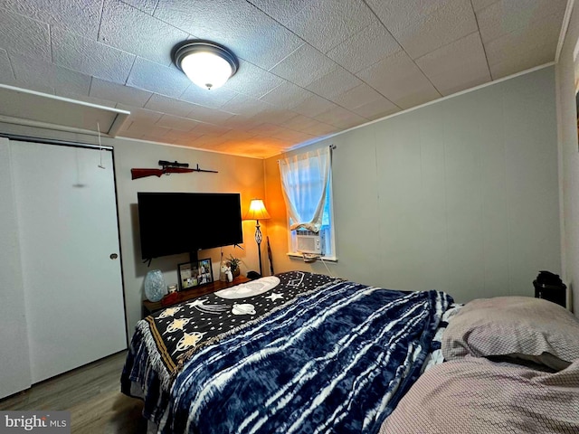 bedroom featuring cooling unit, attic access, and wood finished floors