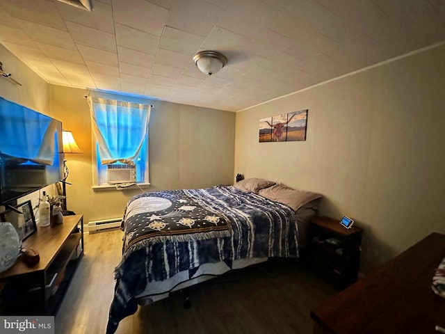 bedroom with a baseboard radiator, cooling unit, and wood finished floors