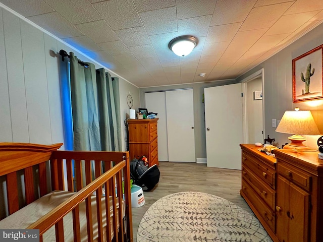 bedroom with a closet, light wood-type flooring, and a nursery area