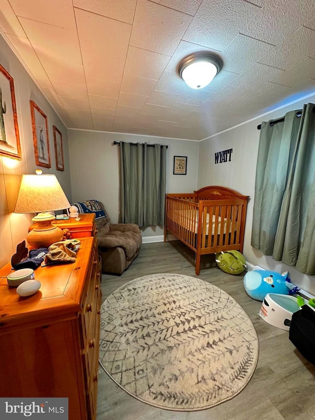 bedroom with a nursery area and wood finished floors