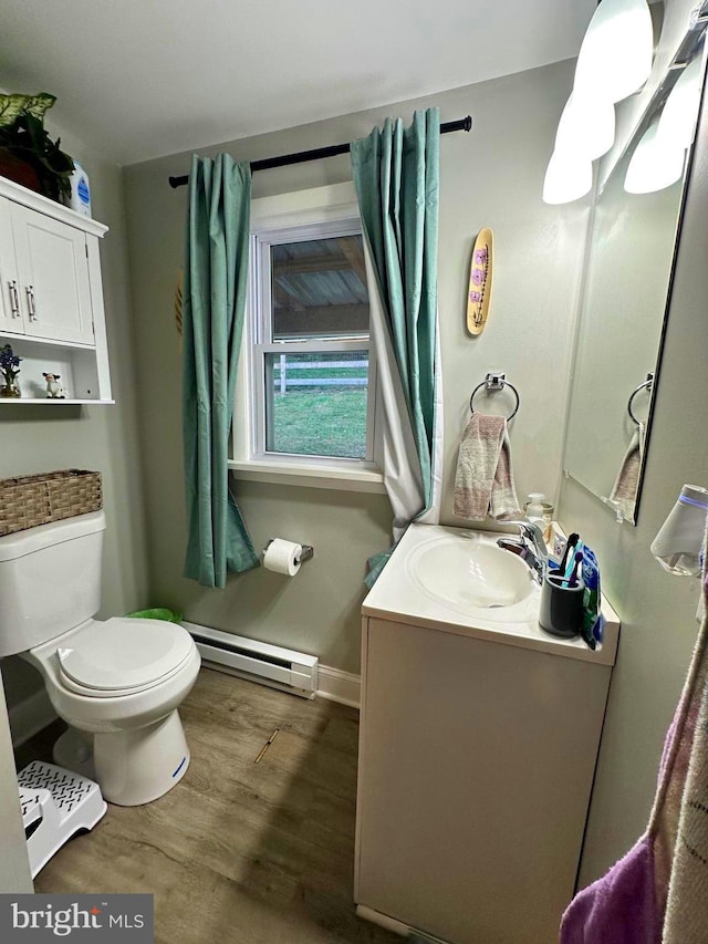 bathroom with vanity, wood finished floors, baseboards, toilet, and baseboard heating