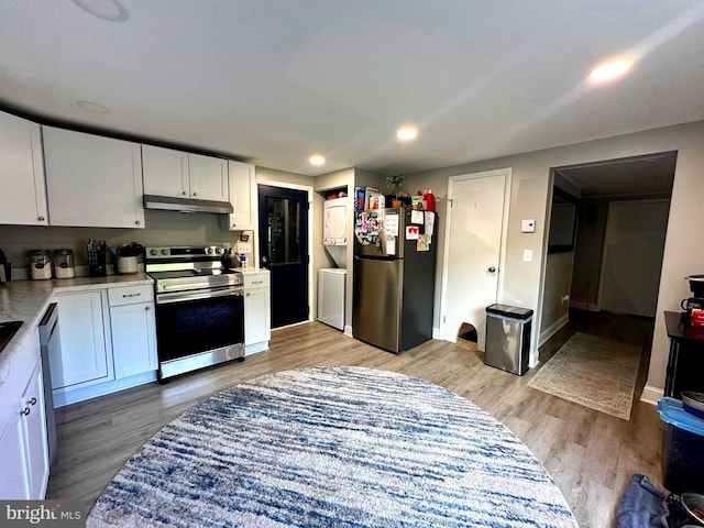 kitchen with stainless steel appliances, light countertops, white cabinets, light wood-style floors, and under cabinet range hood