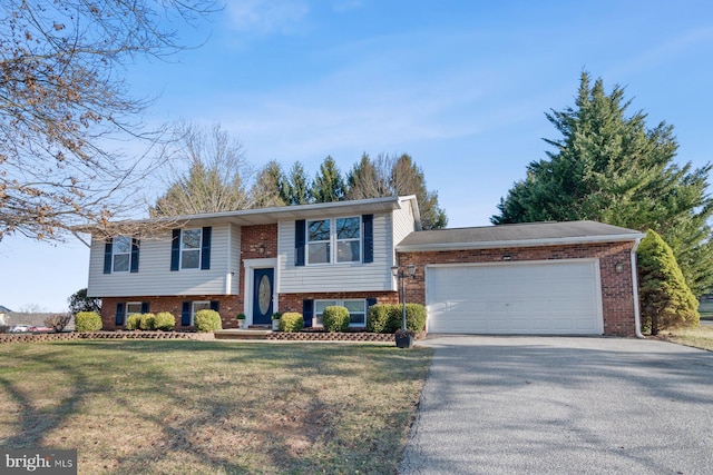 split foyer home with aphalt driveway, a front lawn, brick siding, and an attached garage