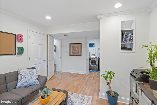 living area with light wood-style flooring, washer / clothes dryer, baseboards, and ornamental molding