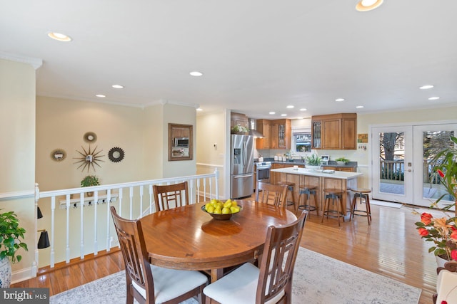 dining space with recessed lighting, light wood-type flooring, ornamental molding, and french doors