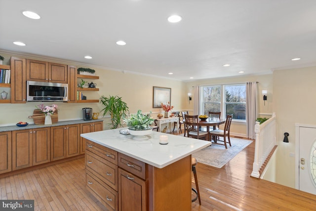 kitchen with brown cabinetry, stainless steel microwave, and open shelves