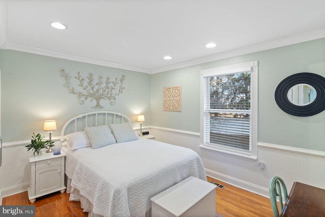 bedroom with visible vents, crown molding, and wood finished floors