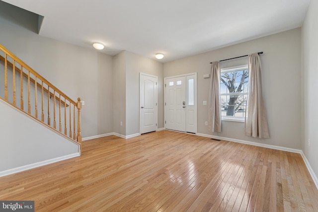 foyer entrance featuring hardwood / wood-style floors, stairway, and baseboards