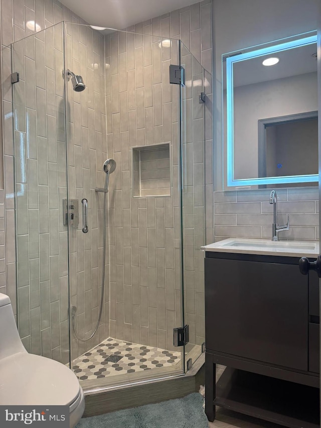 bathroom with vanity, decorative backsplash, toilet, and a stall shower