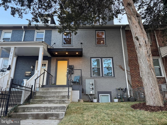 multi unit property with brick siding, a front yard, and fence