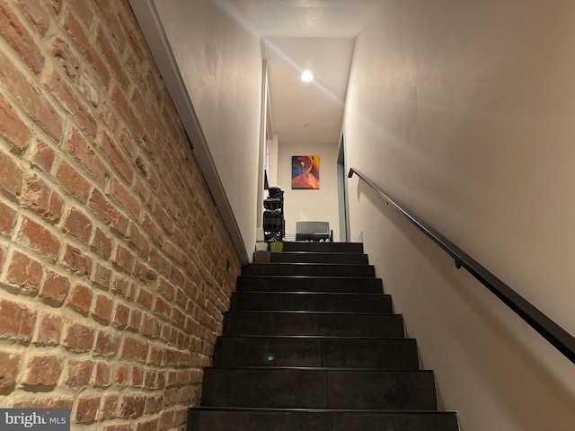 staircase featuring brick wall