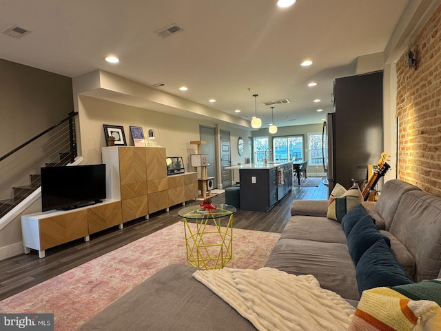 living area with visible vents, dark wood-type flooring, and stairs