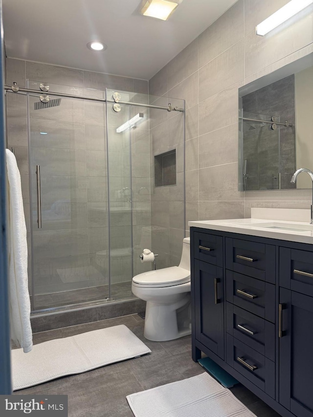 full bathroom featuring toilet, tile walls, a shower stall, and vanity