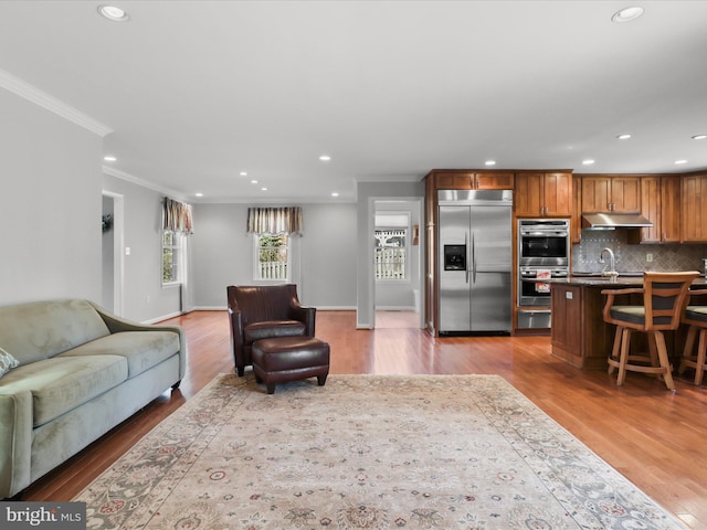 living area featuring recessed lighting, light wood-style floors, baseboards, and ornamental molding